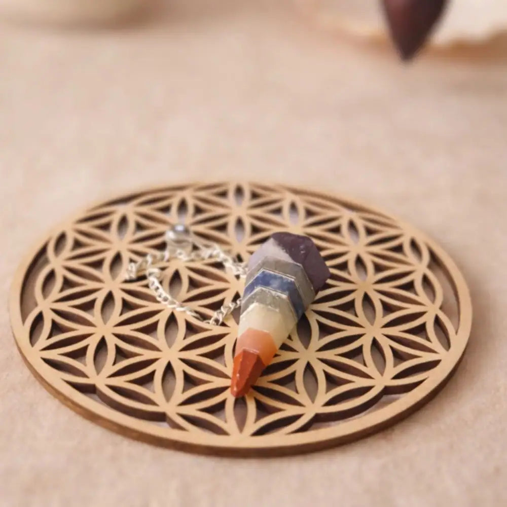 pendule 7 chakra en rechargement sur une fleur de vie en bois