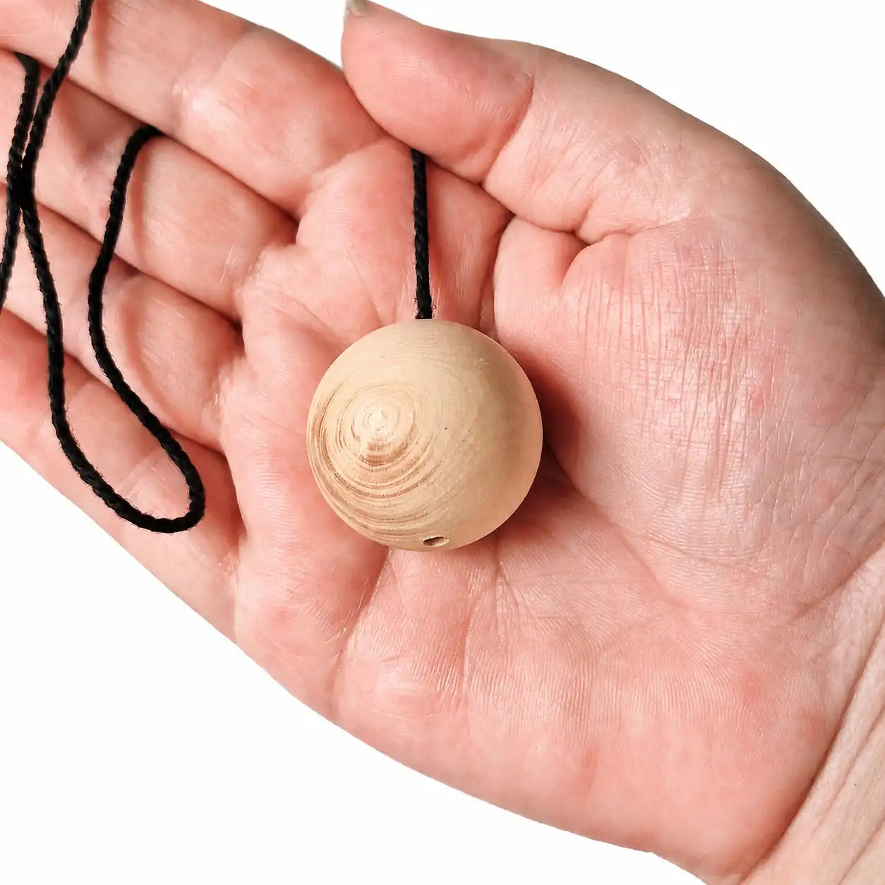 Pendule boule en bois de buis naturel tenu dans la main