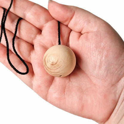 Pendule boule en bois de buis naturel tenu dans la main