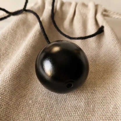 Gros plan sur un pendule boule en bois noir poli