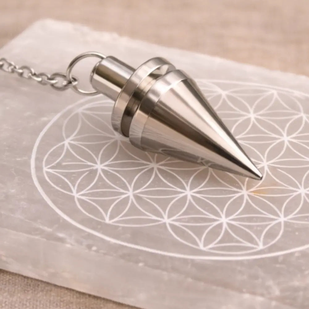 pendule conique en metal sur une plaque de fleur de vie