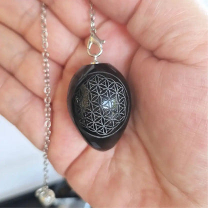 Pendule Fleur de Vie en obsidienne noire présenté dans une main