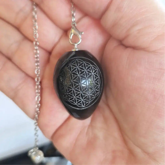 Pendule Fleur de Vie en obsidienne noire présenté dans une main