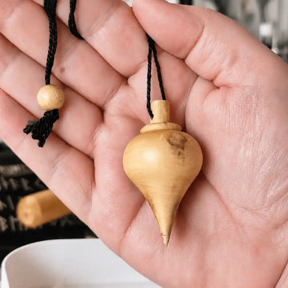 Pendule goutte en bois de buis tenu dans la main