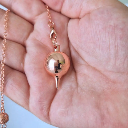 Pendule goutte couleur cuivre tenu dans la main
