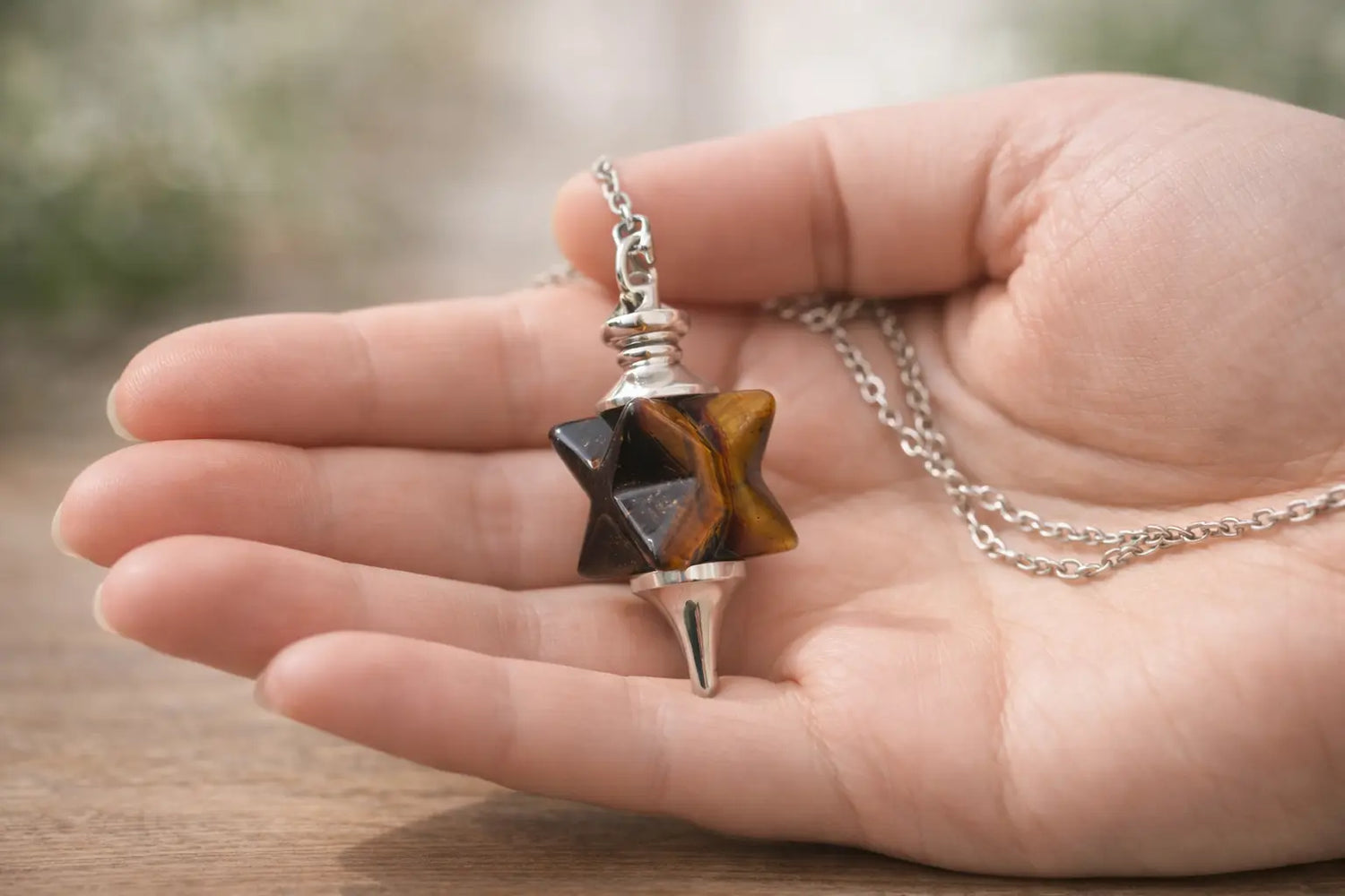 pendule merkaba oeil de tigre dans main