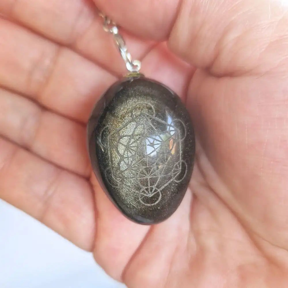 Pendule Métatron en obsidienne dorée présenté dans une main