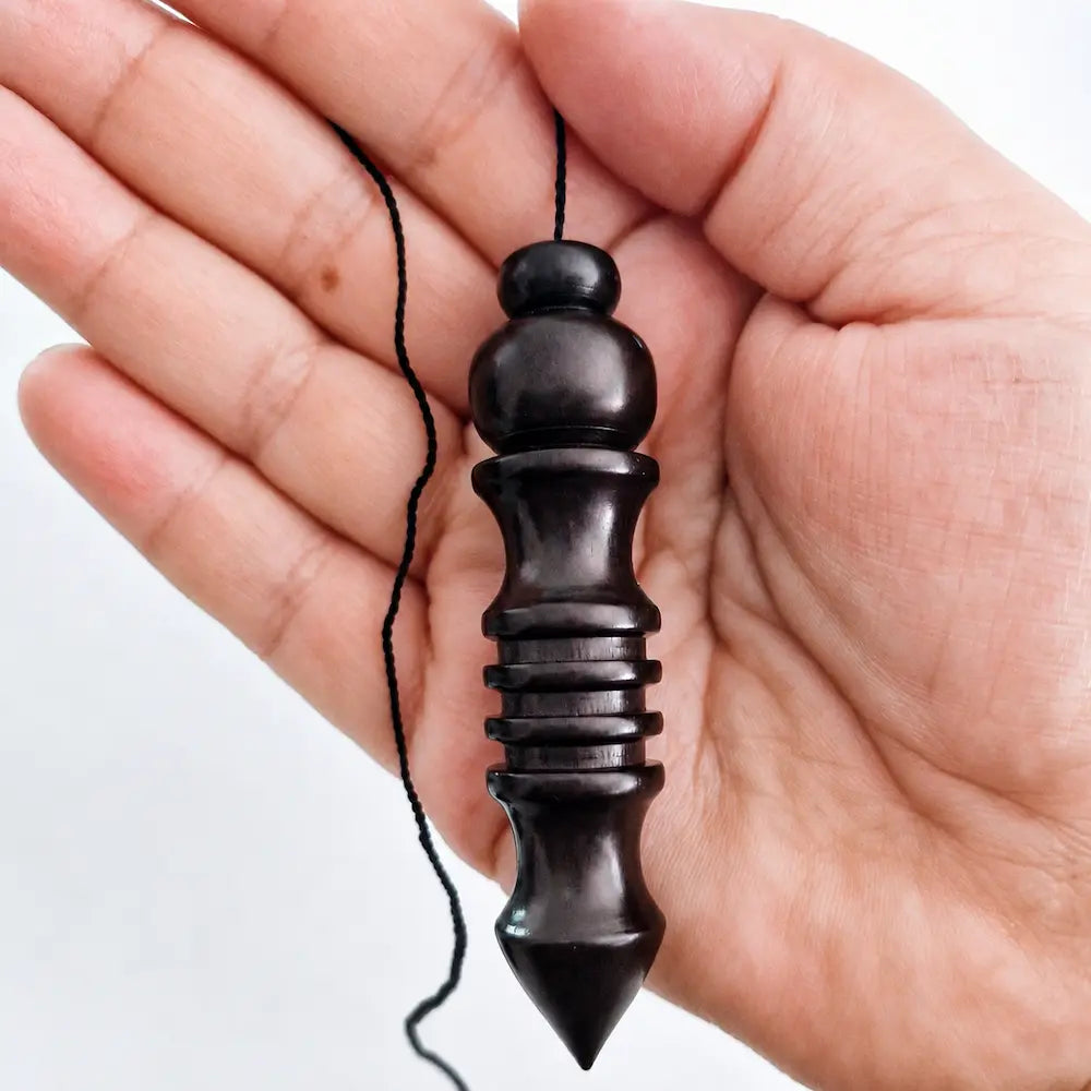 Pendule Osiris en bois noir présenté dans la main