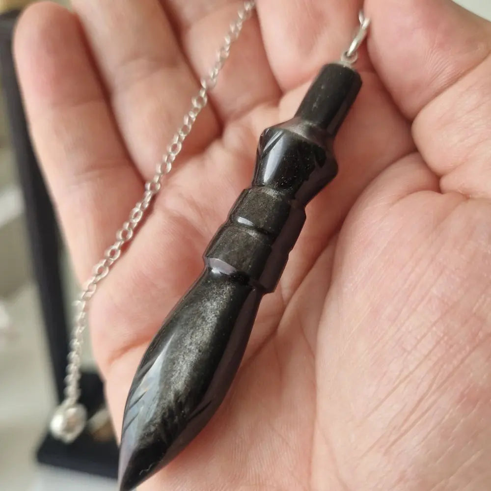 Pendule Thot en obsidienne argentée tenu en main