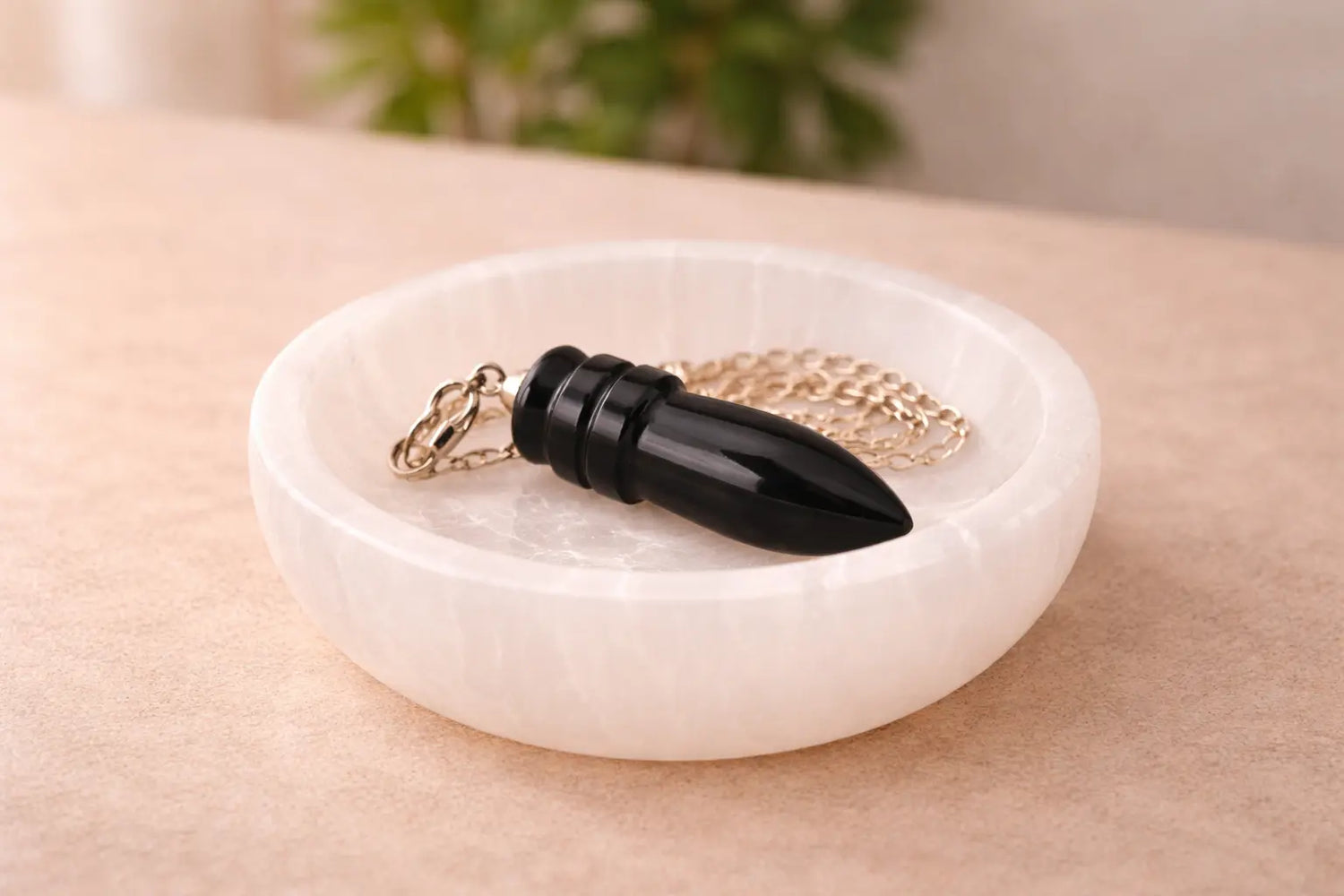 pendule egyptien en obsidienne dans un bol de sélénite