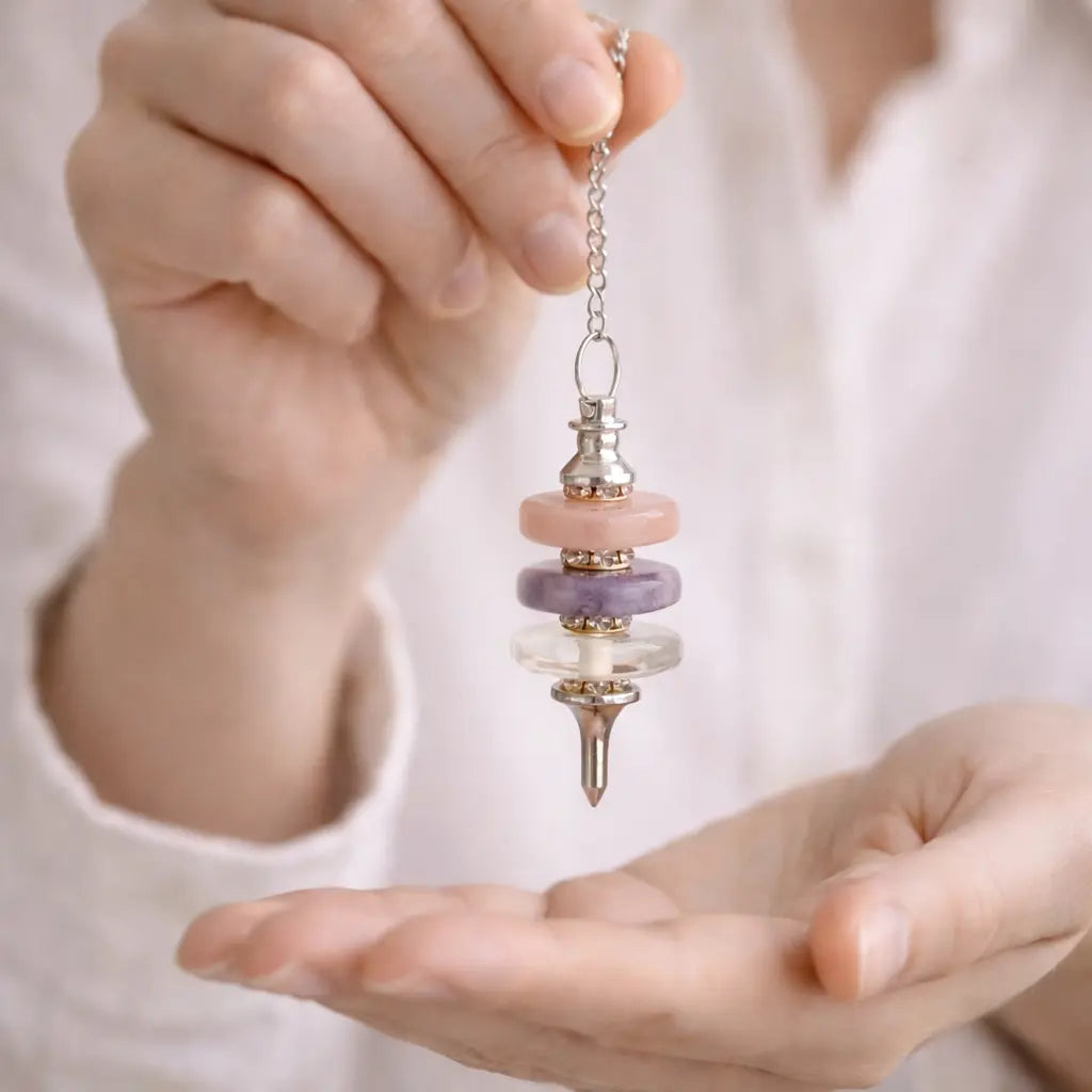Gros plan sur le pendule divinatoire triple disque  cristal de roche , améthyste et quartz rose